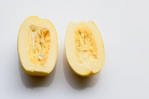 Fresh spaghetti squash cut in half on white background